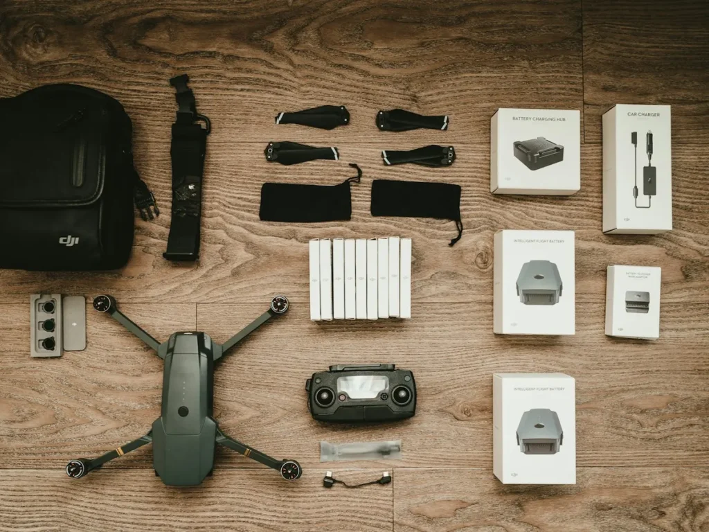Drone DJI com controle, bolsa, hélices e acessórios organizados sobre mesa de madeira