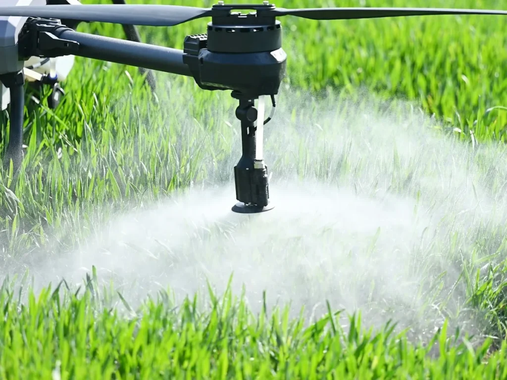 Drone agrícola em voo baixo pulverizando uma plantação verde