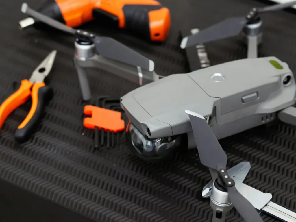 Drone DJI Mavic sobre bancada escura com alicate, chave e ferramentas