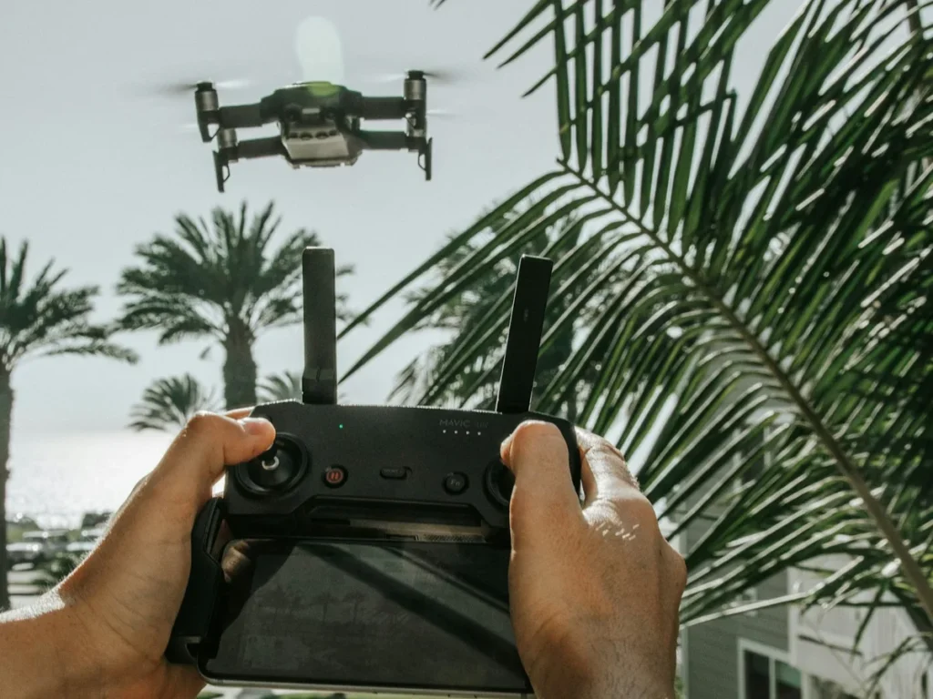 Piloto segurando o controle enquanto um drone DJI voa entre coqueiros