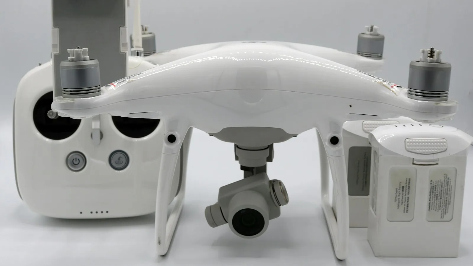 Drone DJI Phantom ao lado de baterias inteligentes sobre fundo claro