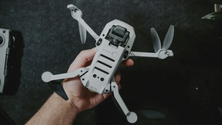 Mão segurando um drone DJI Mini com os braços abertos antes do voo