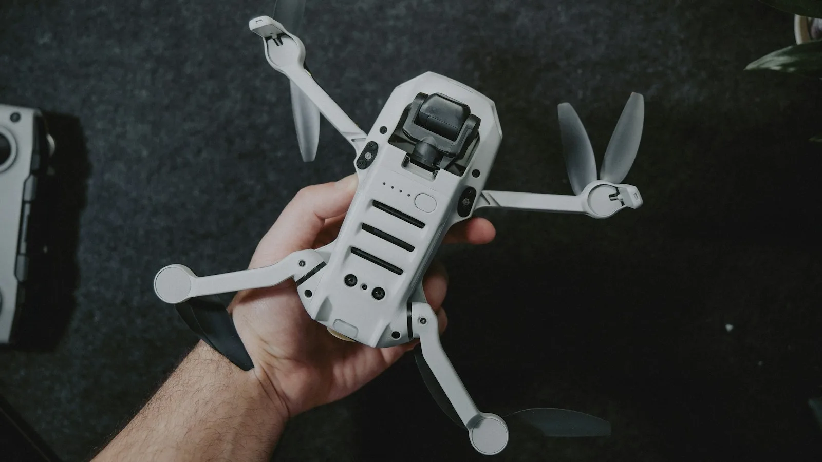 Mão segurando um drone DJI Mini com os braços abertos antes do voo