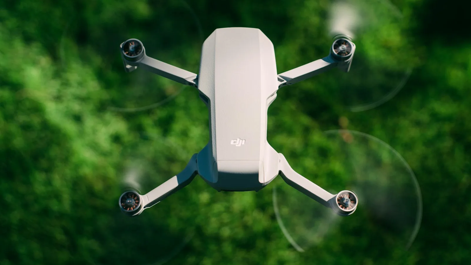 Drone DJI Mini branco em voo sobre gramado verde
