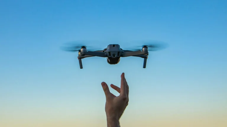 Drone pairando logo acima da mão do piloto com céu ao entardecer