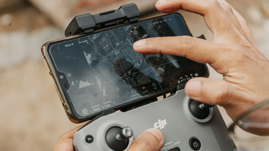 Mãos de um piloto usando o controle DJI com o celular encaixado