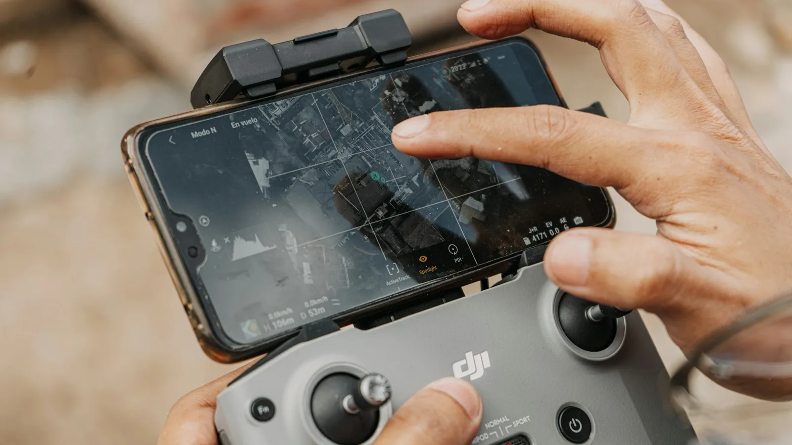 Mãos de um piloto usando o controle DJI com o celular encaixado